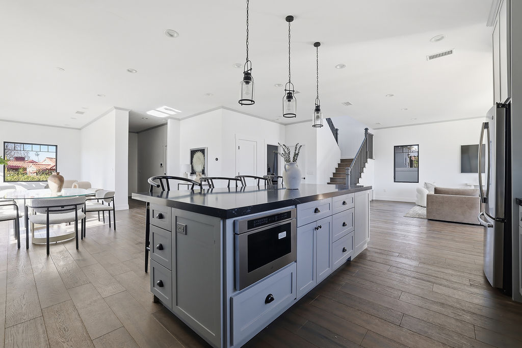 Open kitchen with a gray island, pendant lighting, and adjoining dining and living spaces